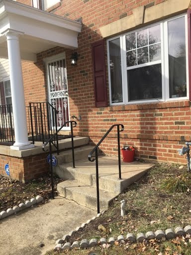 Iron handrail installation in Northwest DC. The two railings are painted black and are installed on two steps leading to the front porch.