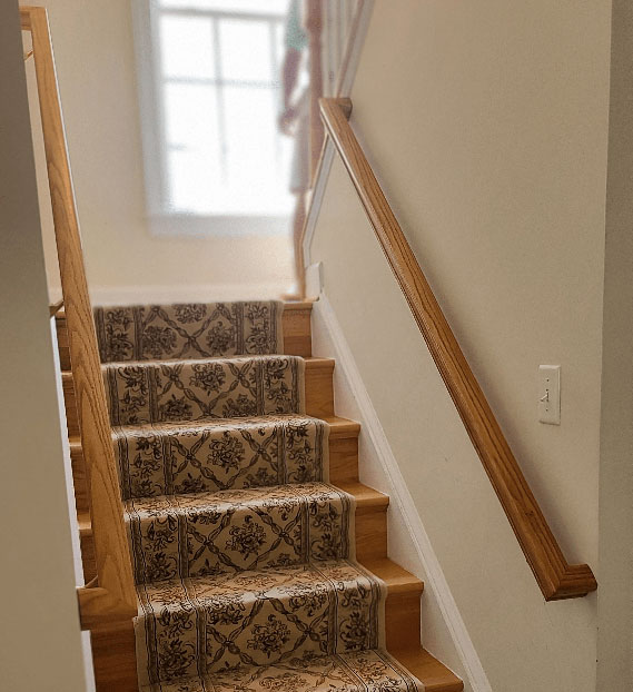 Bannister wood railing installation in Bethesda, MD on both sides of a staircase and stained to match the wooden floor.