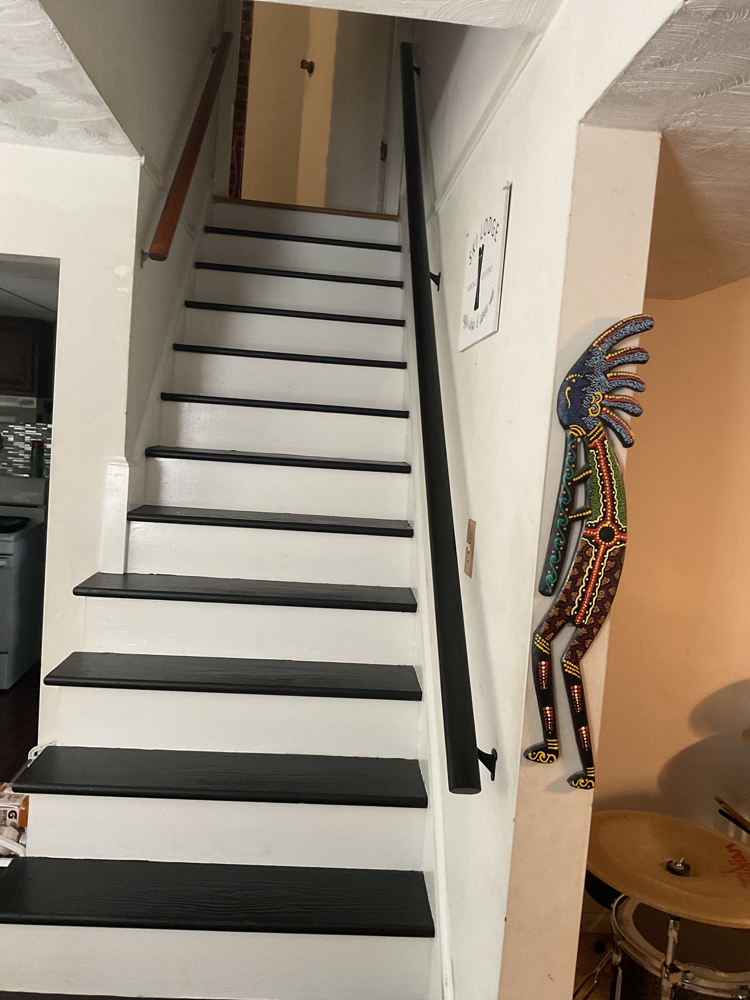 Black wood railing installed on the right of staircase ascending in Chevy Chase, MD, and matches the steps in color black.