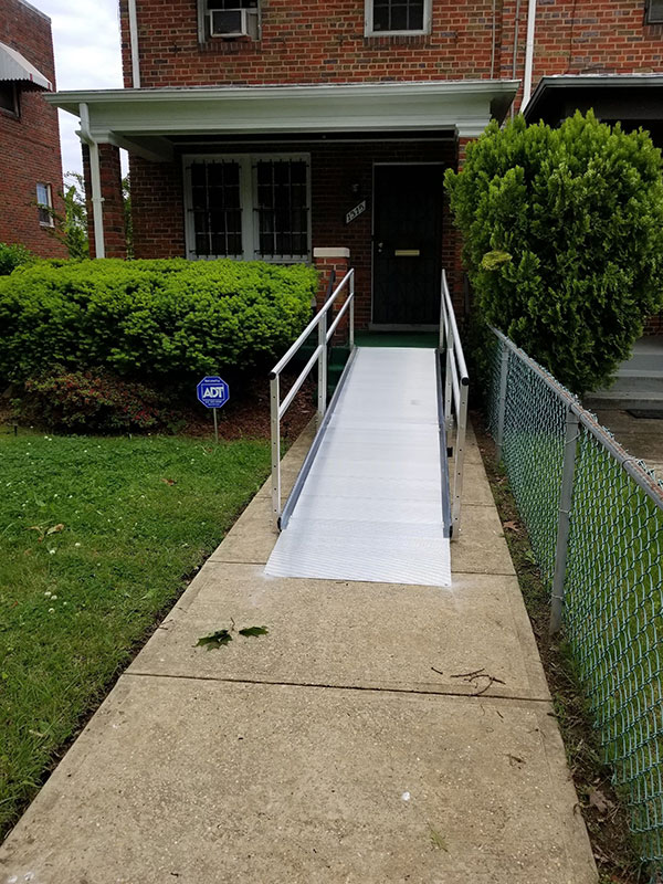 Aluminum Wheelchair Ramp installed in Northwest DC. It is attached to the porch and lands on the concrete pathway leading to the house.